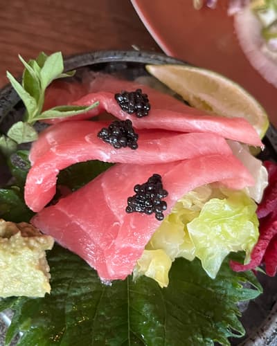 Sashimi van tonijn met caviaar in een stenen kom, op shisoblad