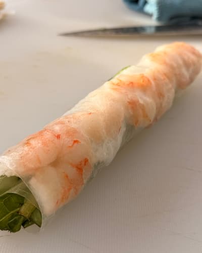 Het afgerolde zomerrolletje, met de garnalen door het rijstpapier heen zichtbaar