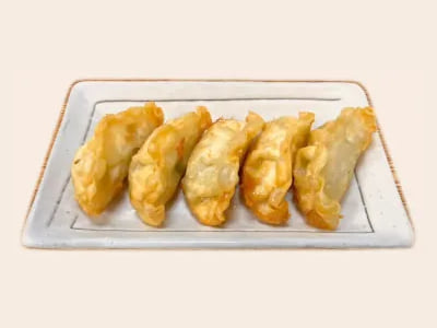 Vijf krokant gebakken gyoza op een rechthoekig bord